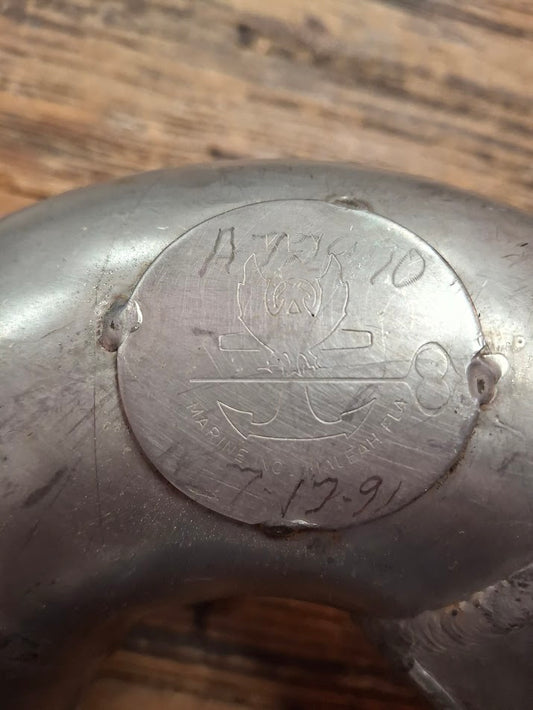 Metal object with engraved text and design on a wooden surface