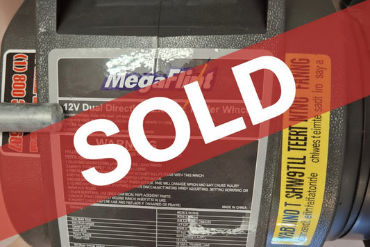 MegaLite 12V dual direction electric trailer winch with label on a wooden surface