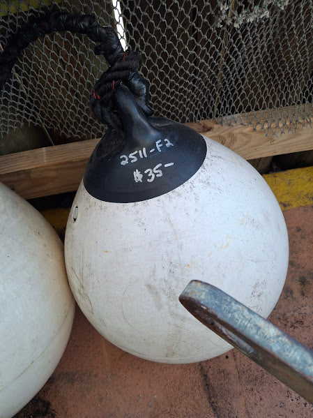 White buoy with black cap and rope, on a textured surface