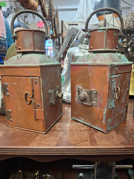 Two vintage copper lanterns on a wooden surface with a blurred background.