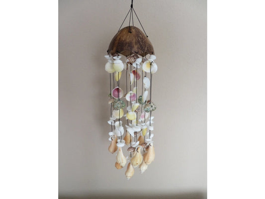 Decorative shell wind chime hanging against a plain wall