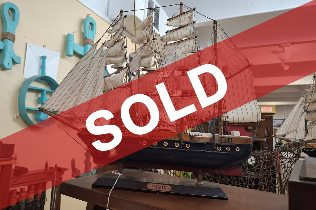 Model ship with multiple sails on a wooden base indoors