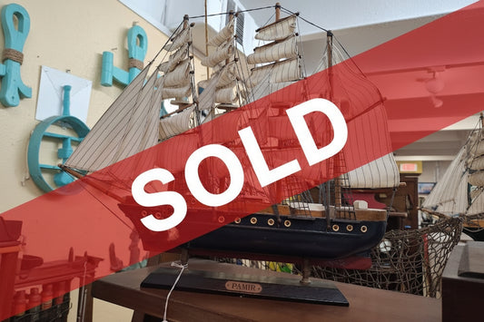 Model ship with multiple sails on a wooden base indoors