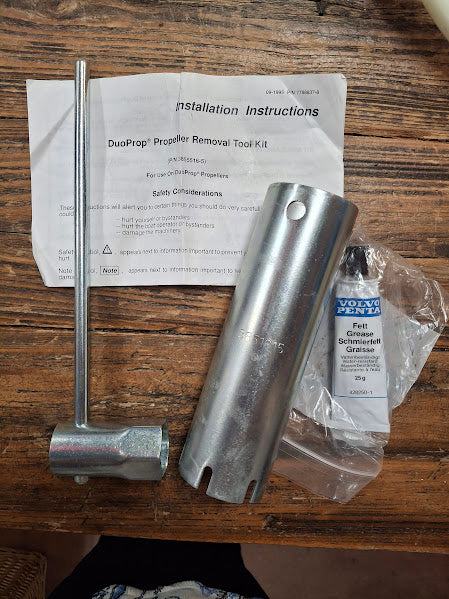 Metal prop wrench with installation instructions and a small container on a wooden surface