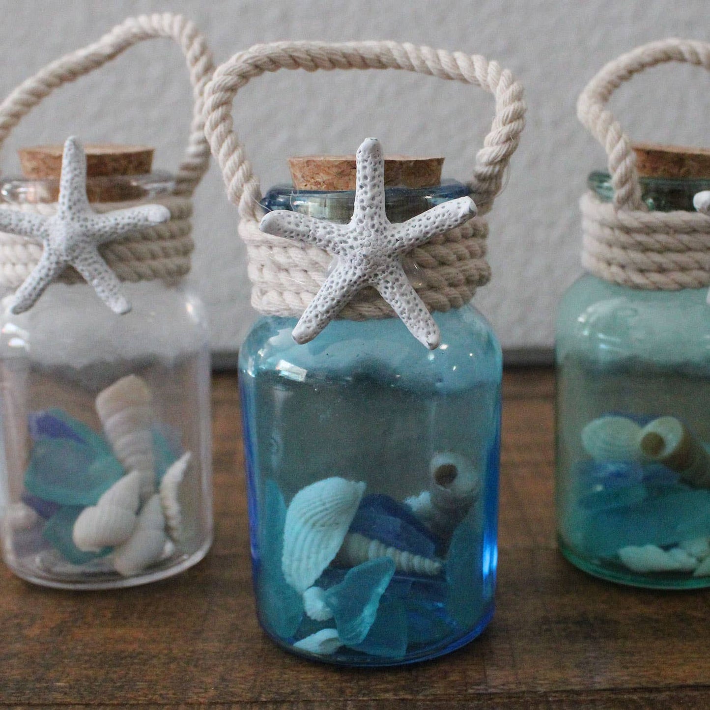 Decorative colored small bottles with starfish, seashells, on a wooden surface.