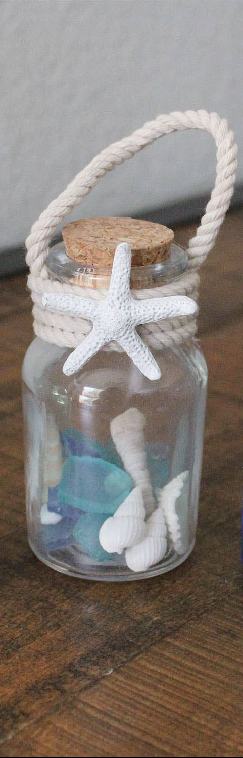 Decorative jar with starfish, shells, and rope handle on a wooden surface