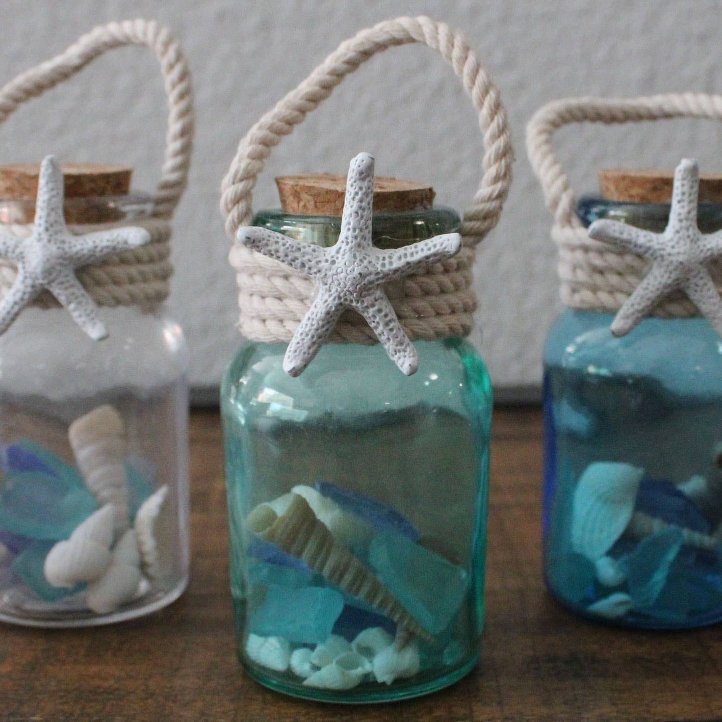 Decorative bottles with starfish and cork lids on a wooden surface
