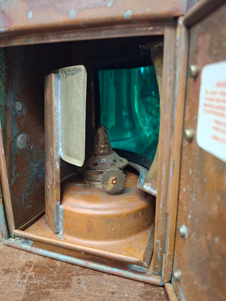 Vintage oil lamp with green glass insert inside a brass casing.
